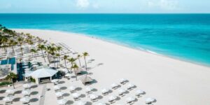 beachfront in aruba overlooking blue ocean with parasols and cabanas