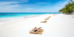 couple on barbados beach sunbathing on loungers on white sand